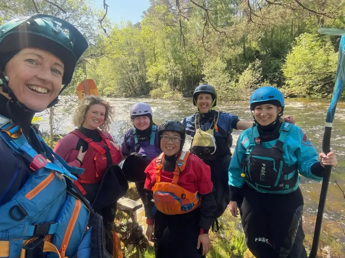 A group of women are posing for a picture in front of a river.