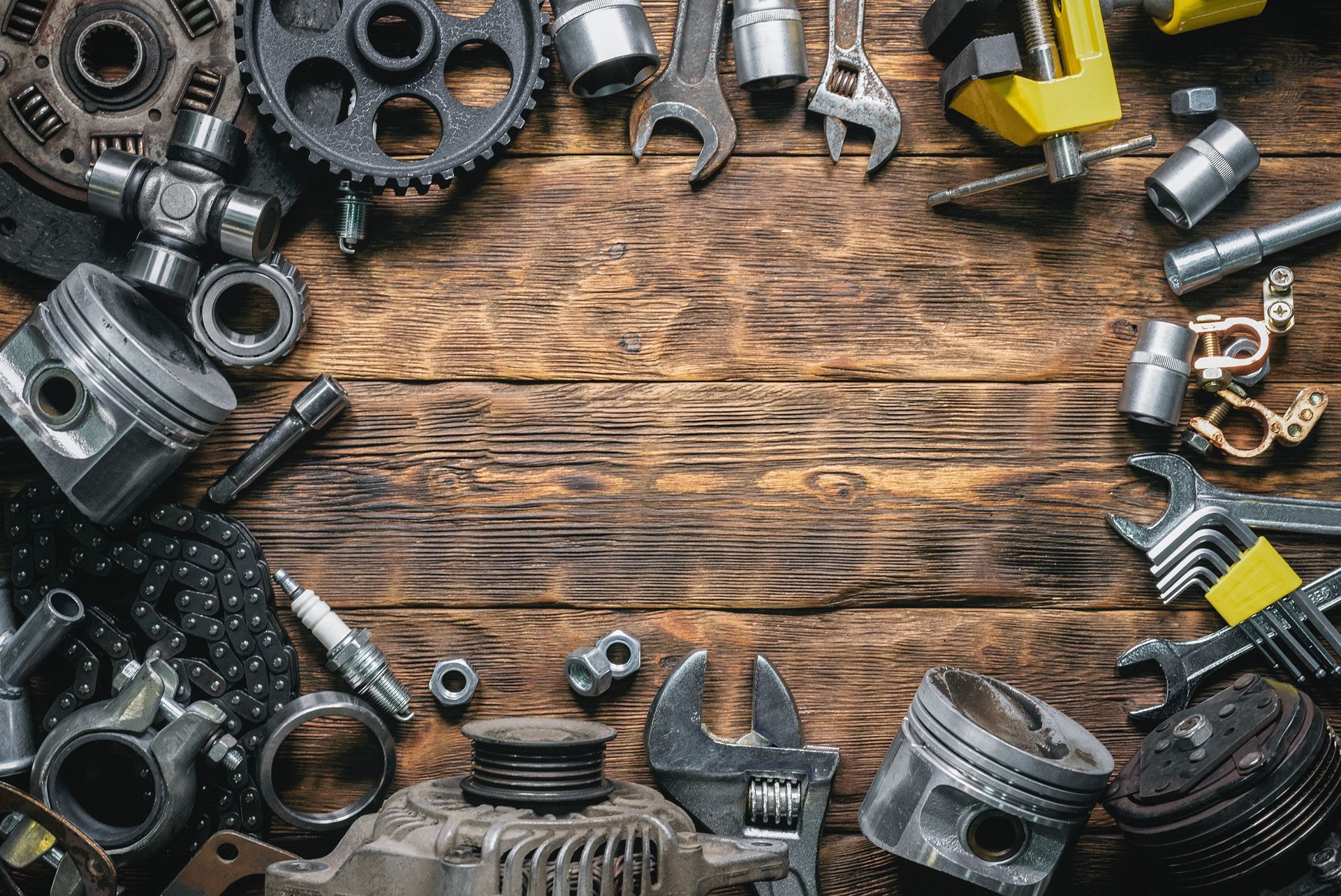 Automotive tools and engine parts arranged on a wooden workbench for vehicle repairs.