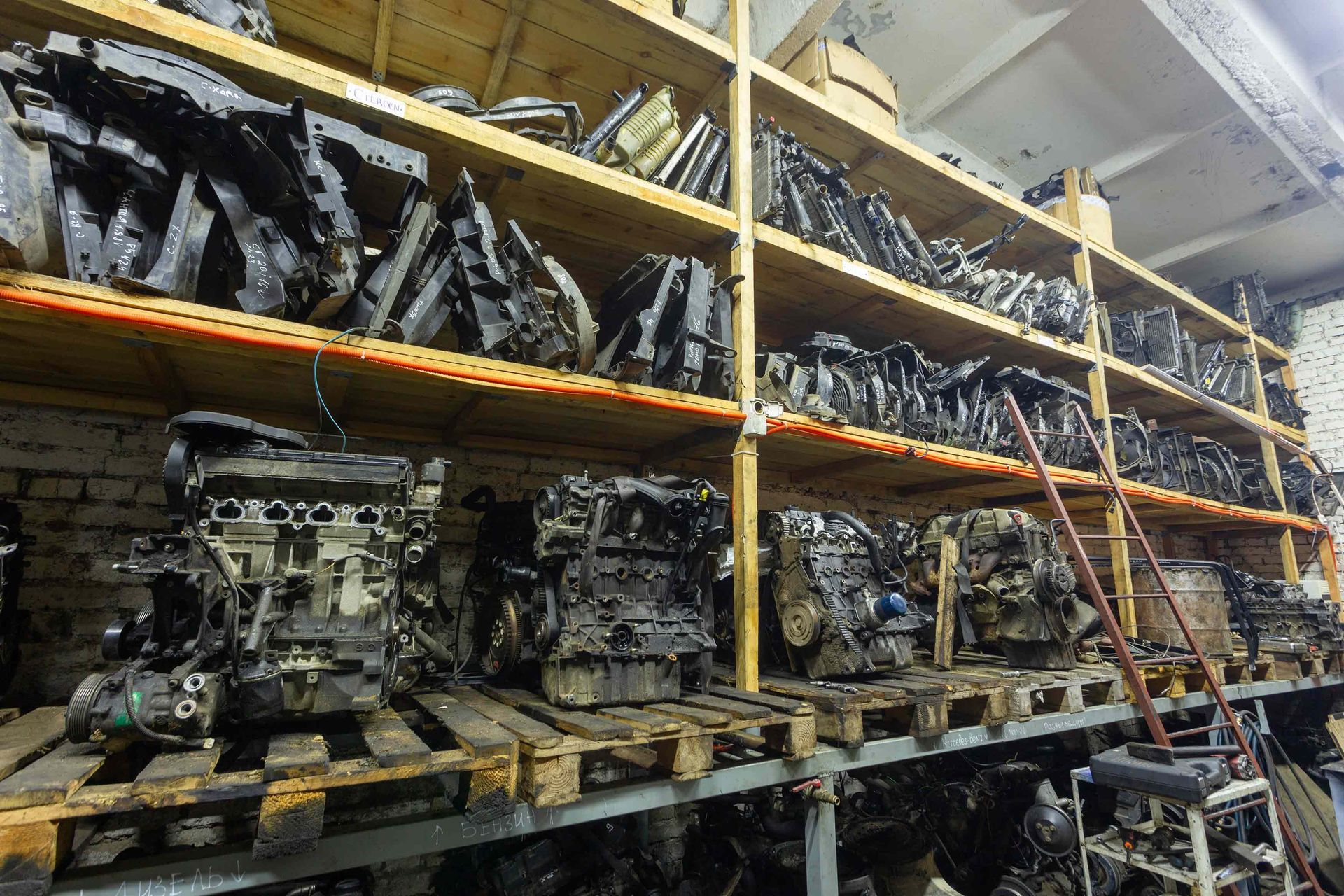 Shelves filled with used car engines and parts stacked in an industrial storage warehouse.