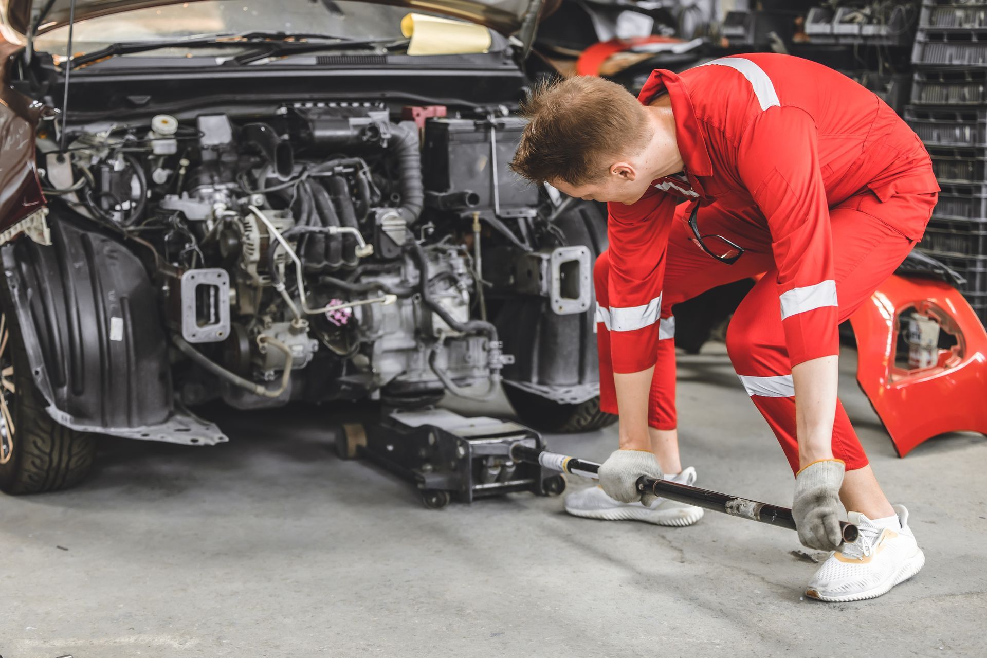 A person in a red jumpsuit is working on a used engine inside a garage or workshop. A person in a red jumpsuit is working on a used engine inside a garage or workshop.