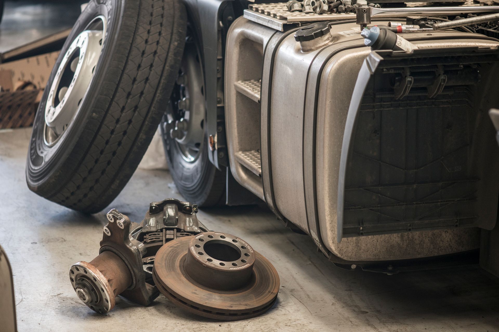 A disassembled truck with used truck parts around it.