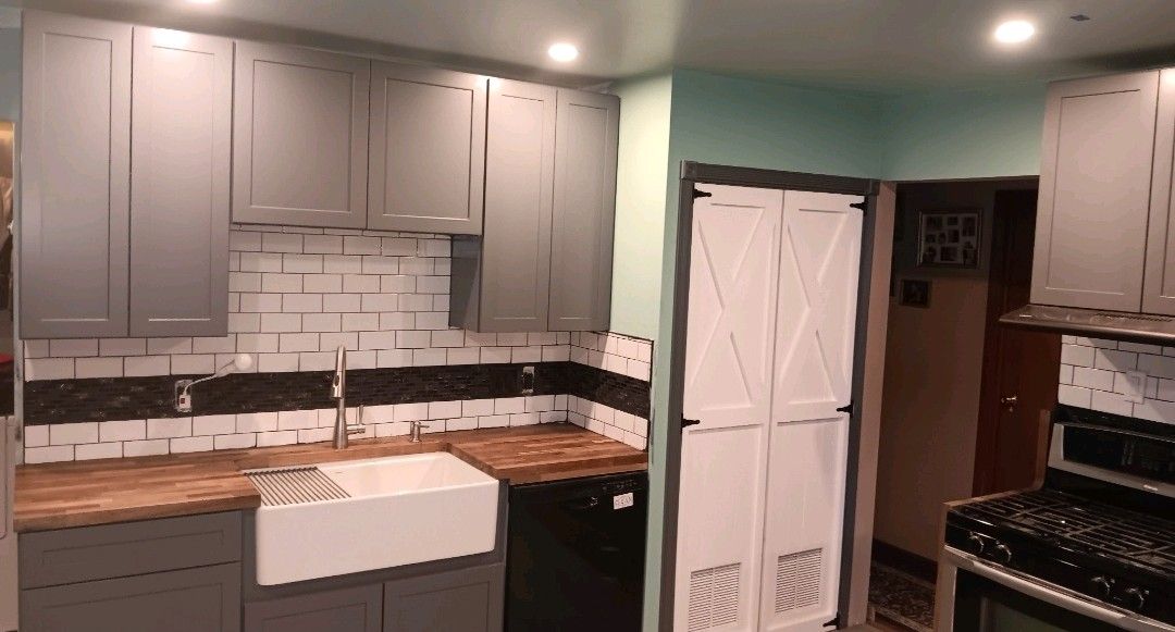 Modern kitchen with gray cabinets, wood countertops, white appliances, and mint green walls.