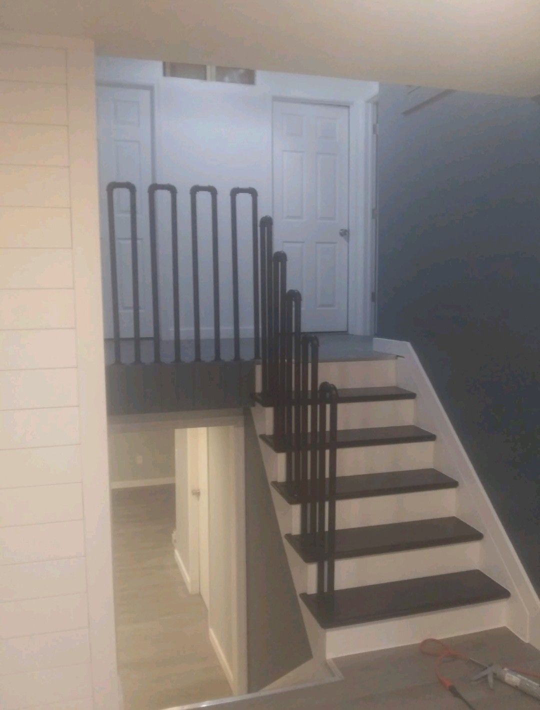 Indoor staircase with black railings leading to a white door on an upper landing.