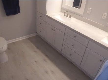 Bathroom with vanity, sink, toilet, and light gray cabinets on a light floor.