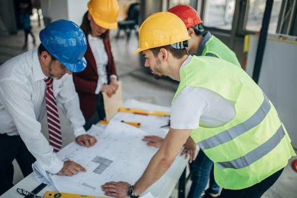 Group of architects working together on construction site, looking at the project plan.