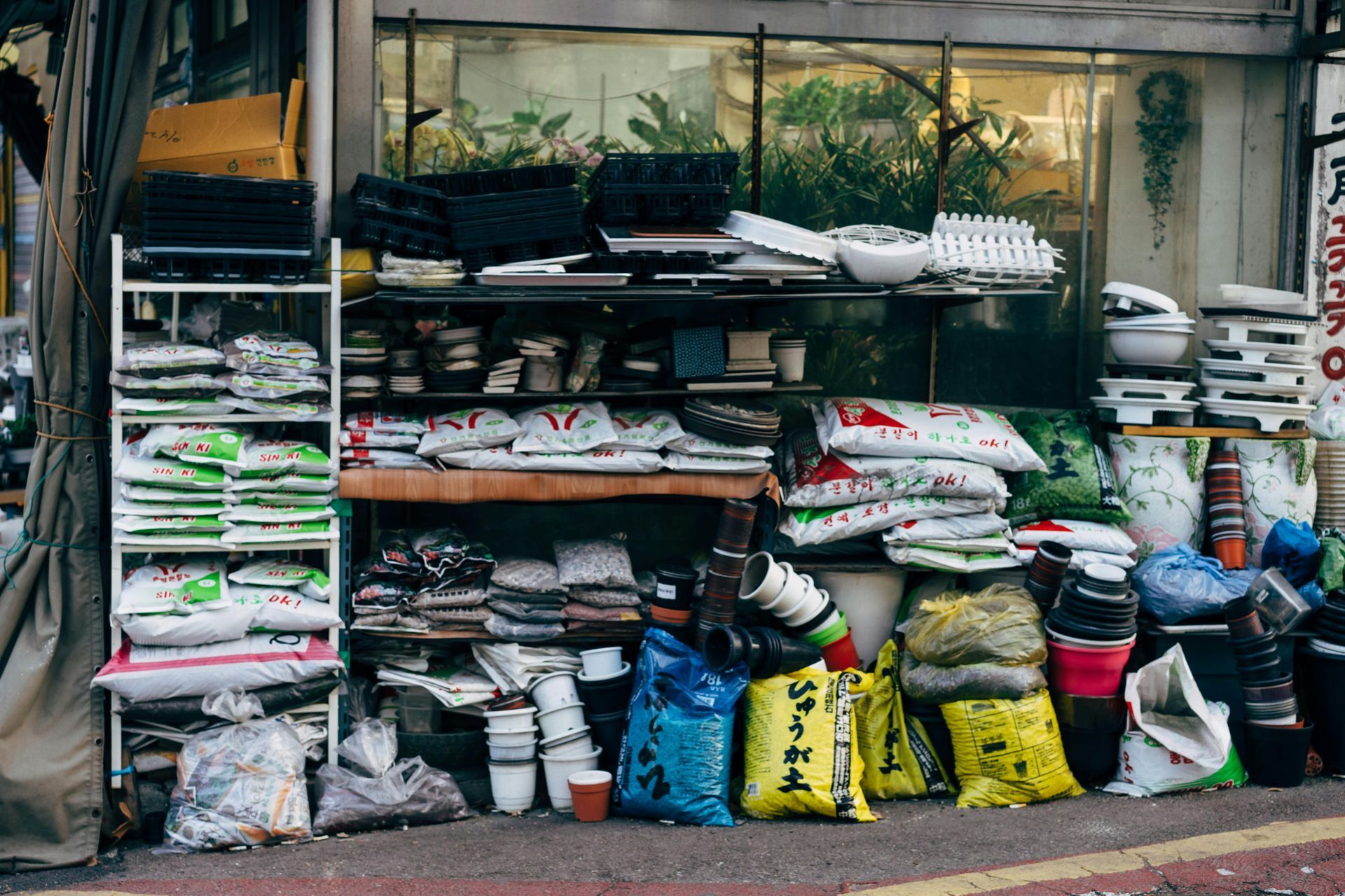 Outdoor storefront stacked with bags of pet supplies and folded goods on shelves