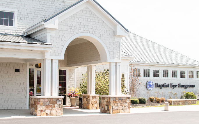 A large white building with a porch and a sign that says rapid eye surgery