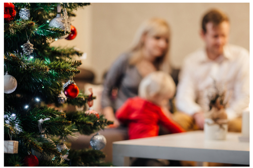 A family is sitting in front of a christmas tree.