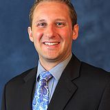 A man in a suit and tie is smiling for the camera.