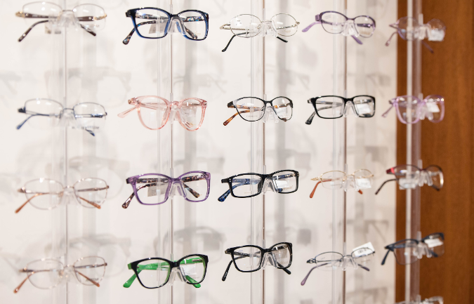 A row of glasses hanging on a wall in an optical shop.