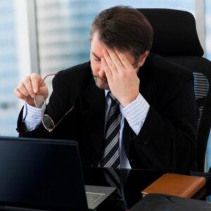 A man in a suit and tie is sitting at a desk with a laptop.