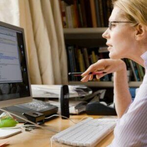 A woman is sitting at a desk looking at a computer screen