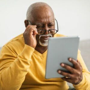 A man wearing glasses is using a tablet computer.