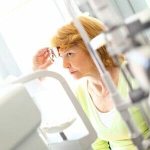 A woman in a green shirt is looking at something in a mirror.