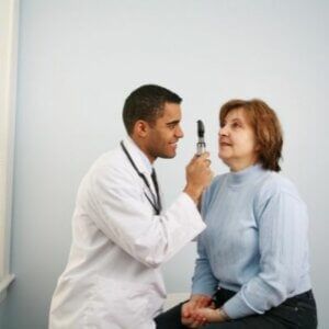 A doctor is examining a woman 's eye with a stethoscope