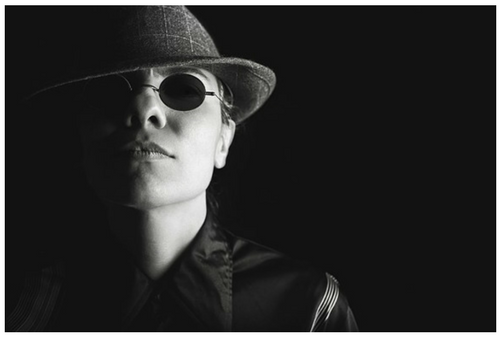 A black and white photo of a man wearing a hat and sunglasses.