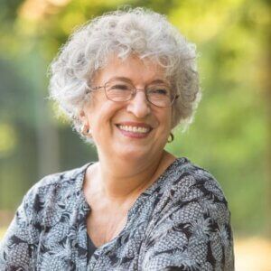 Older woman in glasses sitting outside and smiling