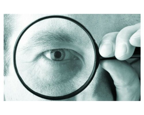A man is looking through a magnifying glass at his eye