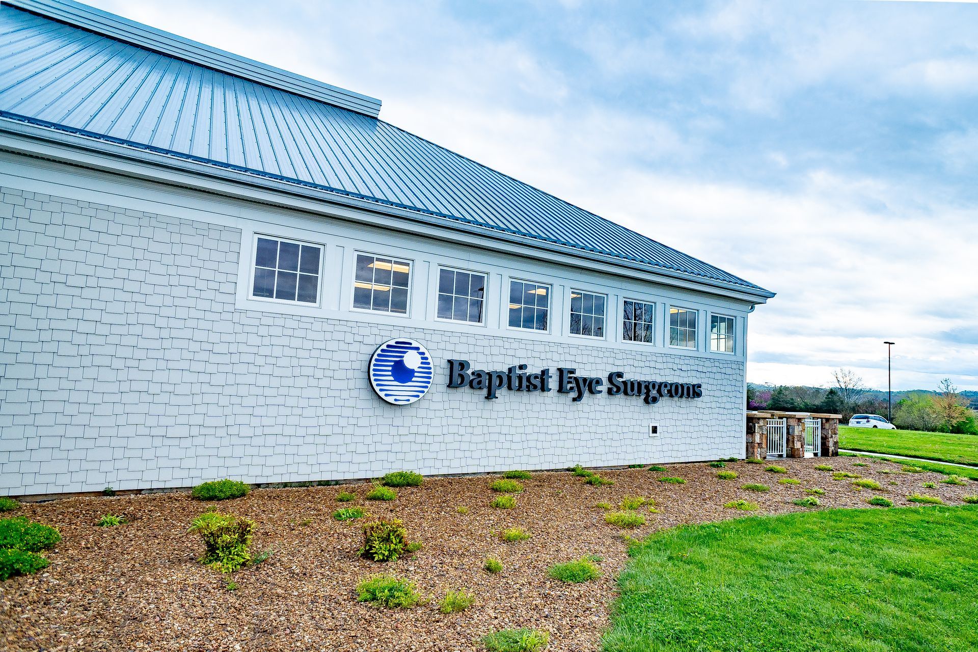 A white brick building with a blue roof and a sign that says baptist eye surgery.