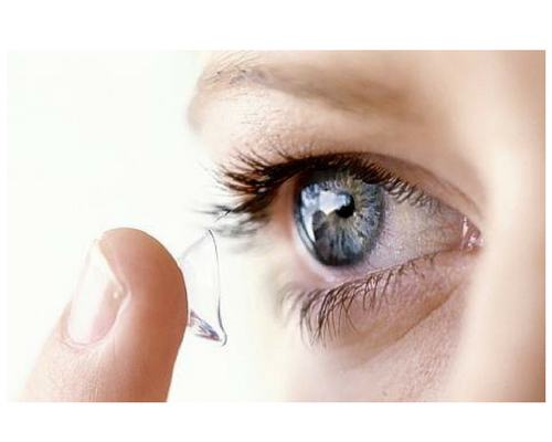 A woman is putting a contact lens in her eye.