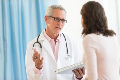 A doctor is talking to a patient while holding a tablet.