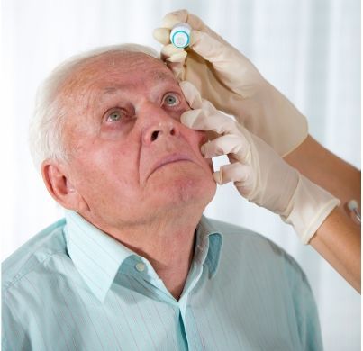 An elderly man is getting his eyes examined by a doctor