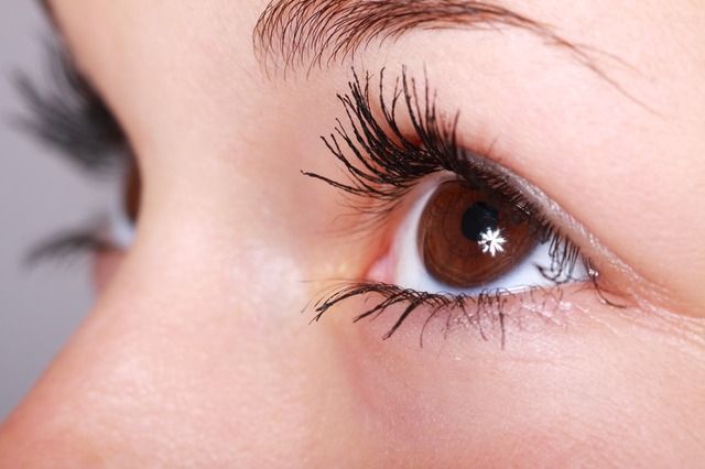 A close up of a woman 's eye with long eyelashes.
