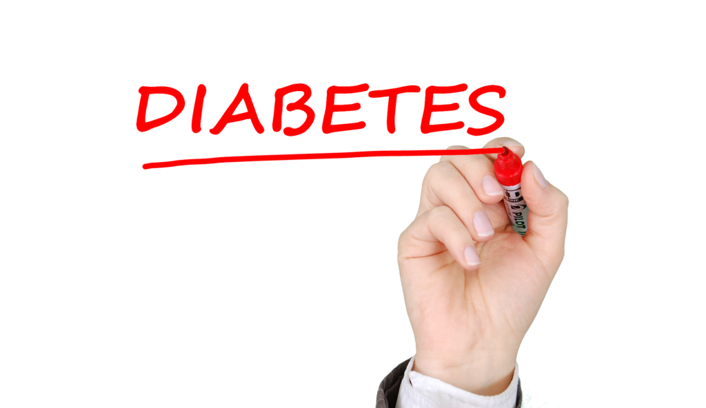 A hand is writing the word diabetes with a marker.