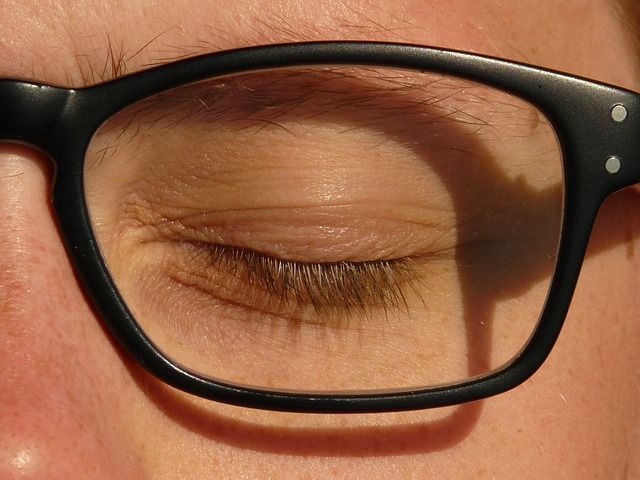 A close up of a person 's eye wearing glasses