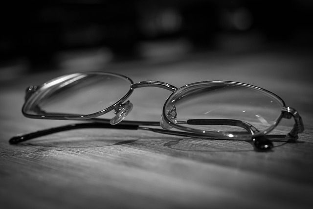 A pair of glasses is sitting on a table in a black and white photo.