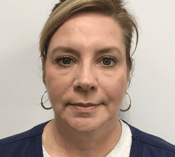 A woman wearing hoop earrings and a blue jacket is looking at the camera.