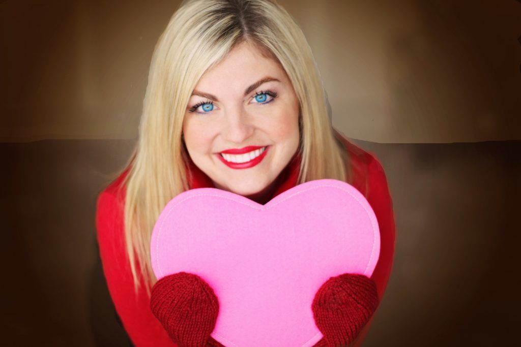 A woman is holding a pink heart in her hands.