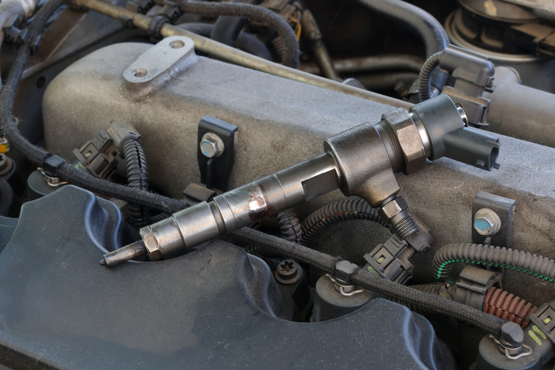Spark plugs and a camshaft laid across a car engine bay for repair or inspection