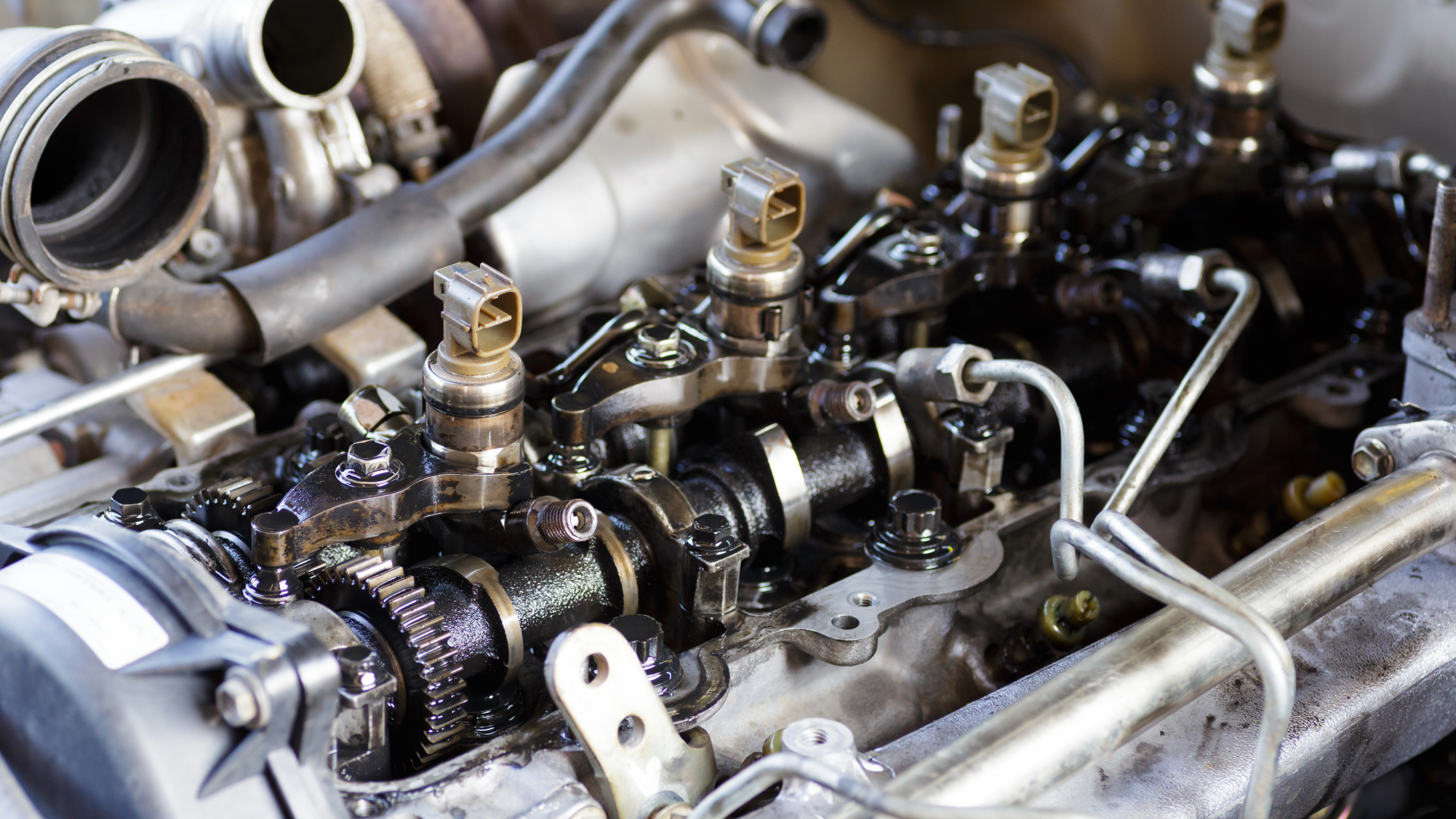 Close-up of a car engine valve train with exposed metal components and hoses