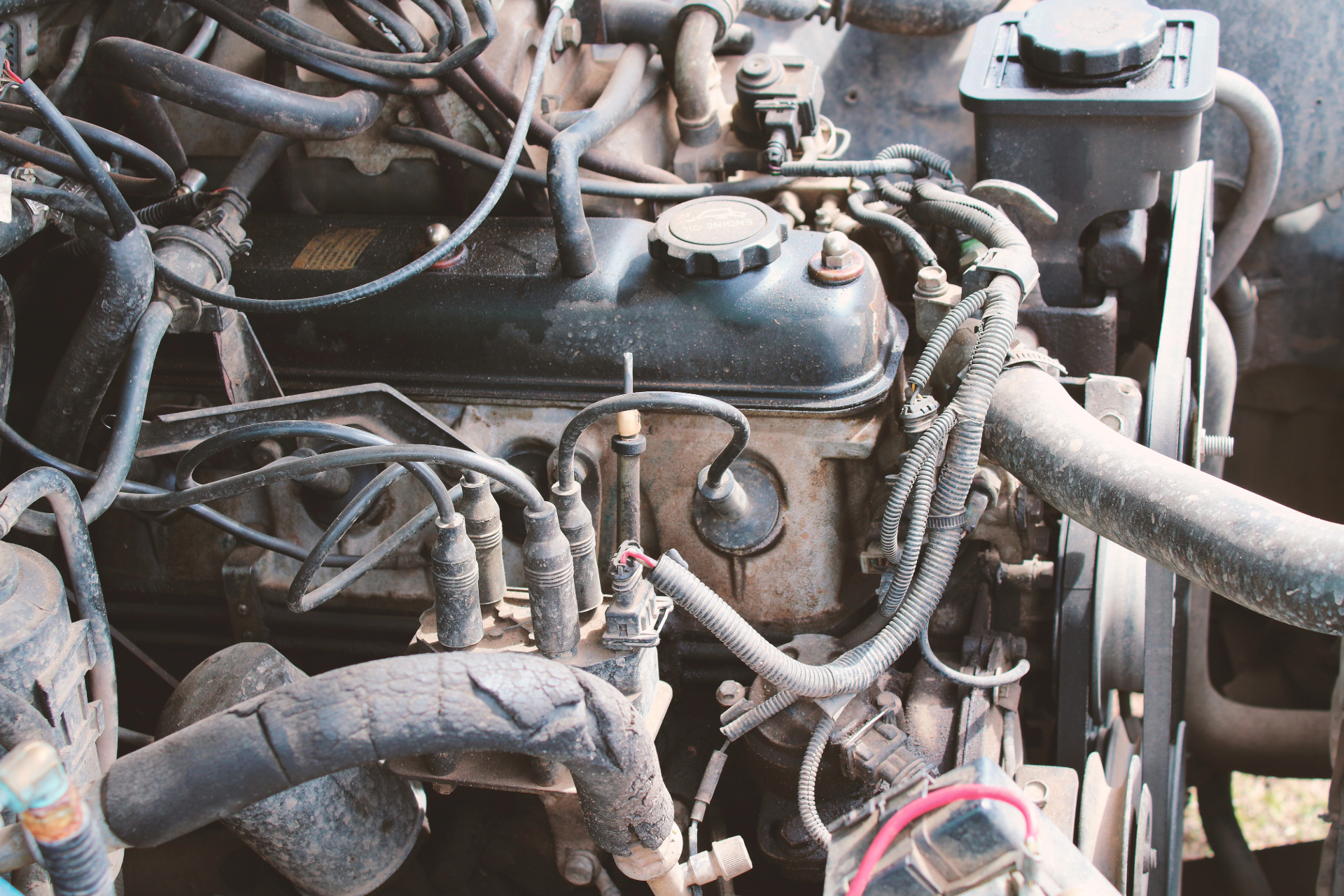 Close-up of a dusty engine with hoses, wires, and metal components in a vehicle bay