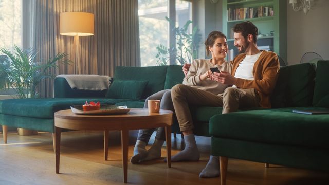 Couple on a couch looking at a phone and smiling