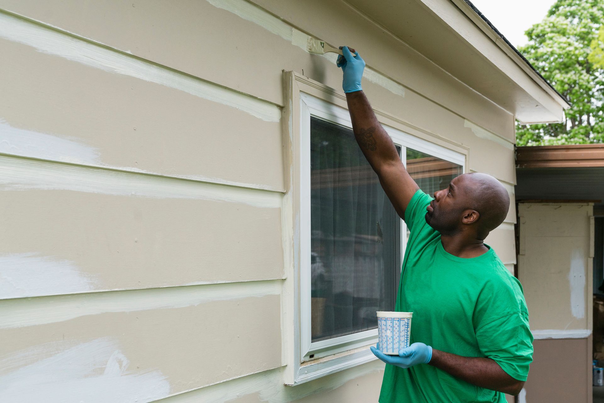 Volunteering man painting siding on house. Volunteering man painting siding on house.