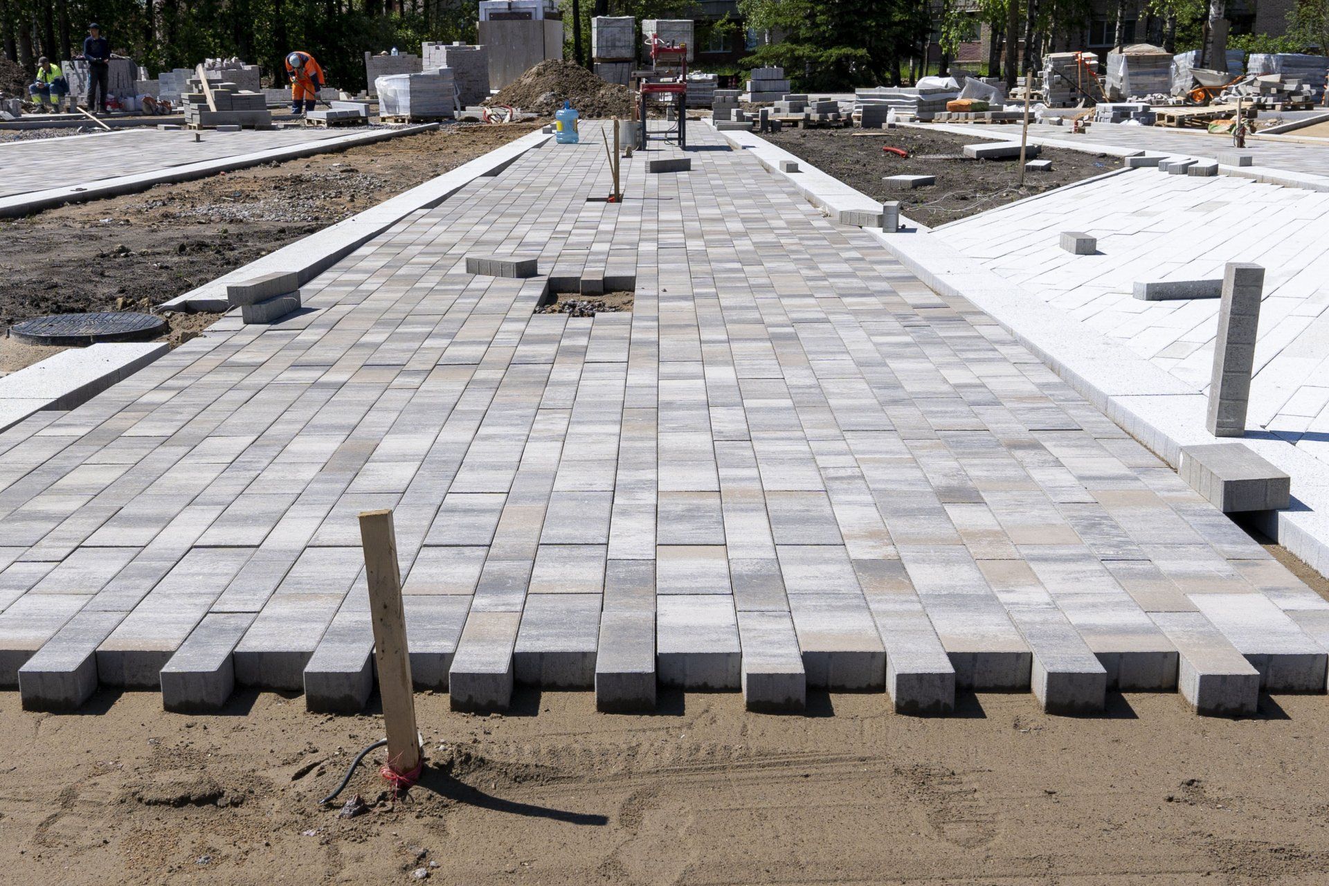 A brick walkway is being built in a park