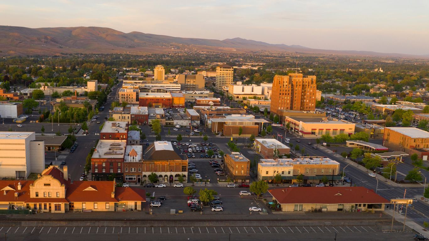 Aerial view of a small downtown with streets, buildings, and mountains at sunset.
