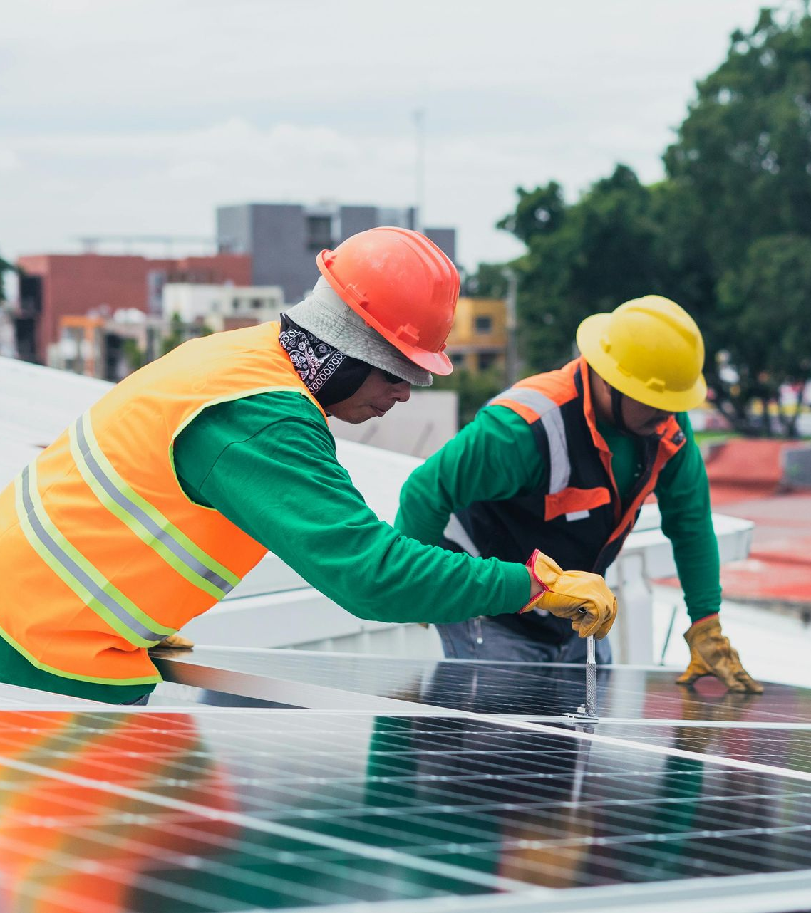 Two workers in safety vests and helmets installing solar panels outdoors