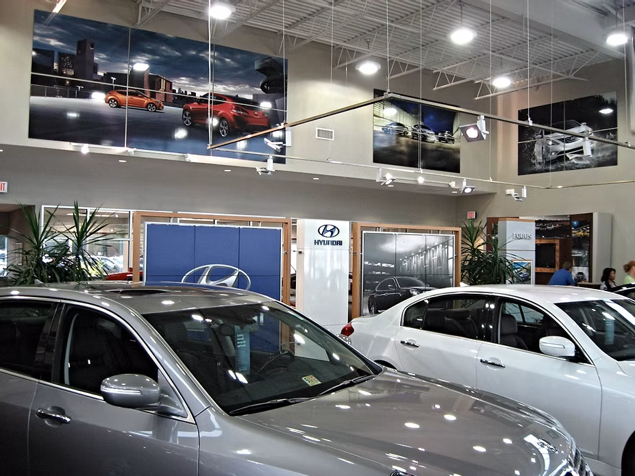 Hyundai car dealership interior with cars on display and promotional posters. Hyundai car dealership interior with cars on display and promotional posters.