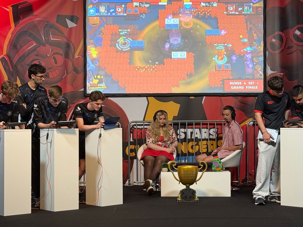 Grand final on stage with teams, caster desk, trophy and screen