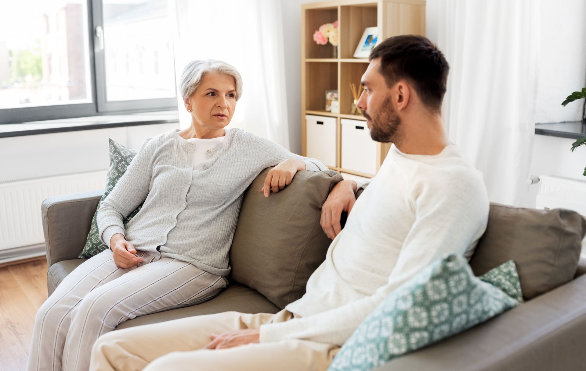A senior mother is talking to her adult son on the couch at home. A senior mother is talking to her adult son on the couch at home.