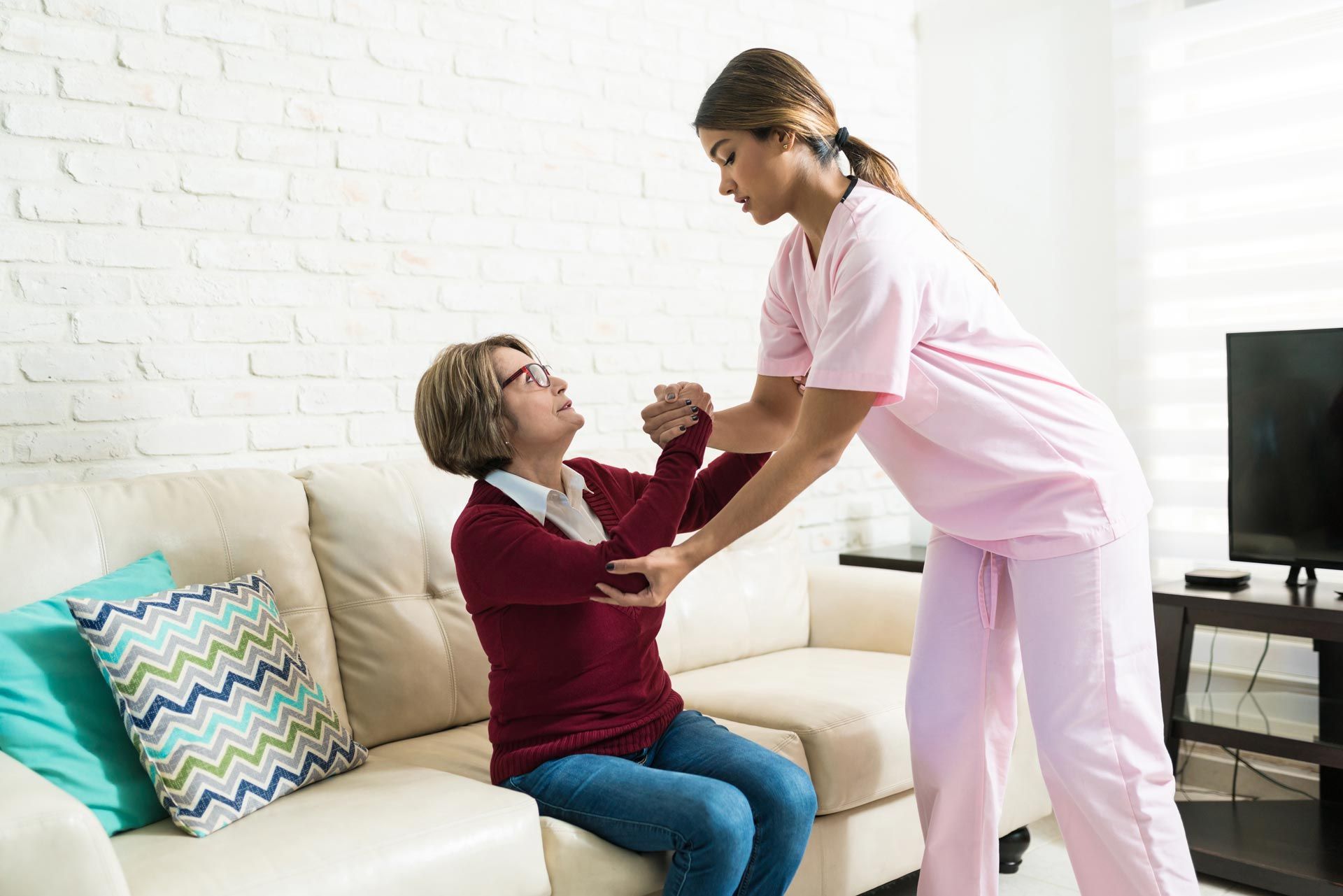 : A caregiver is helping a senior woman to sit.