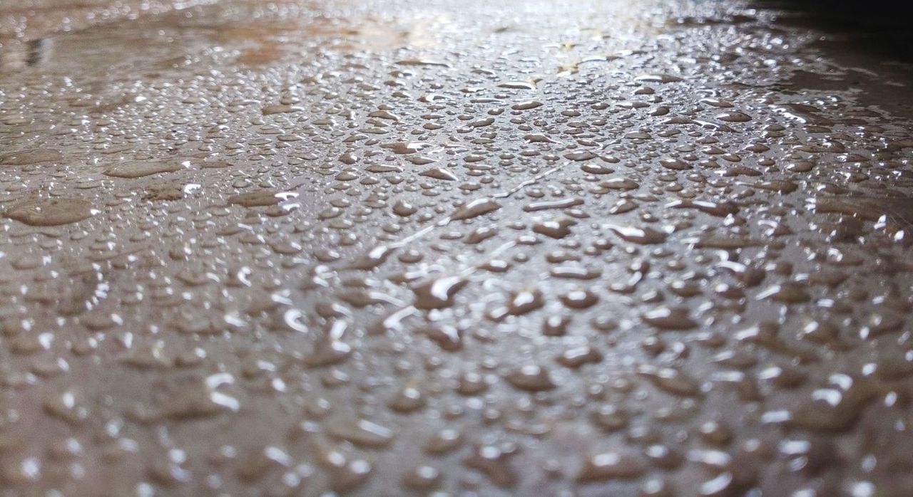 A close up of water drops on a natural stone patio.