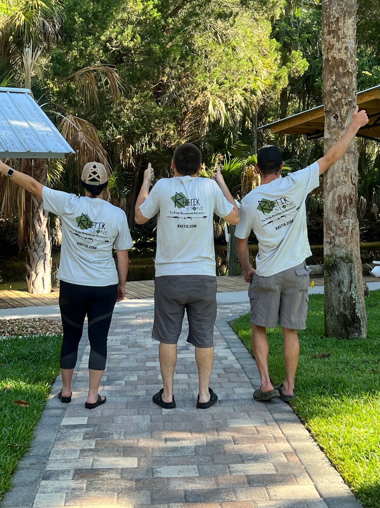 Three people are standing on a path with their arms in the air.