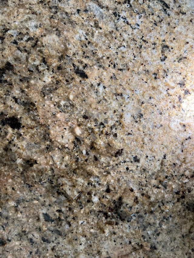A close up of a granite counter top with a lot of small water drops on it.