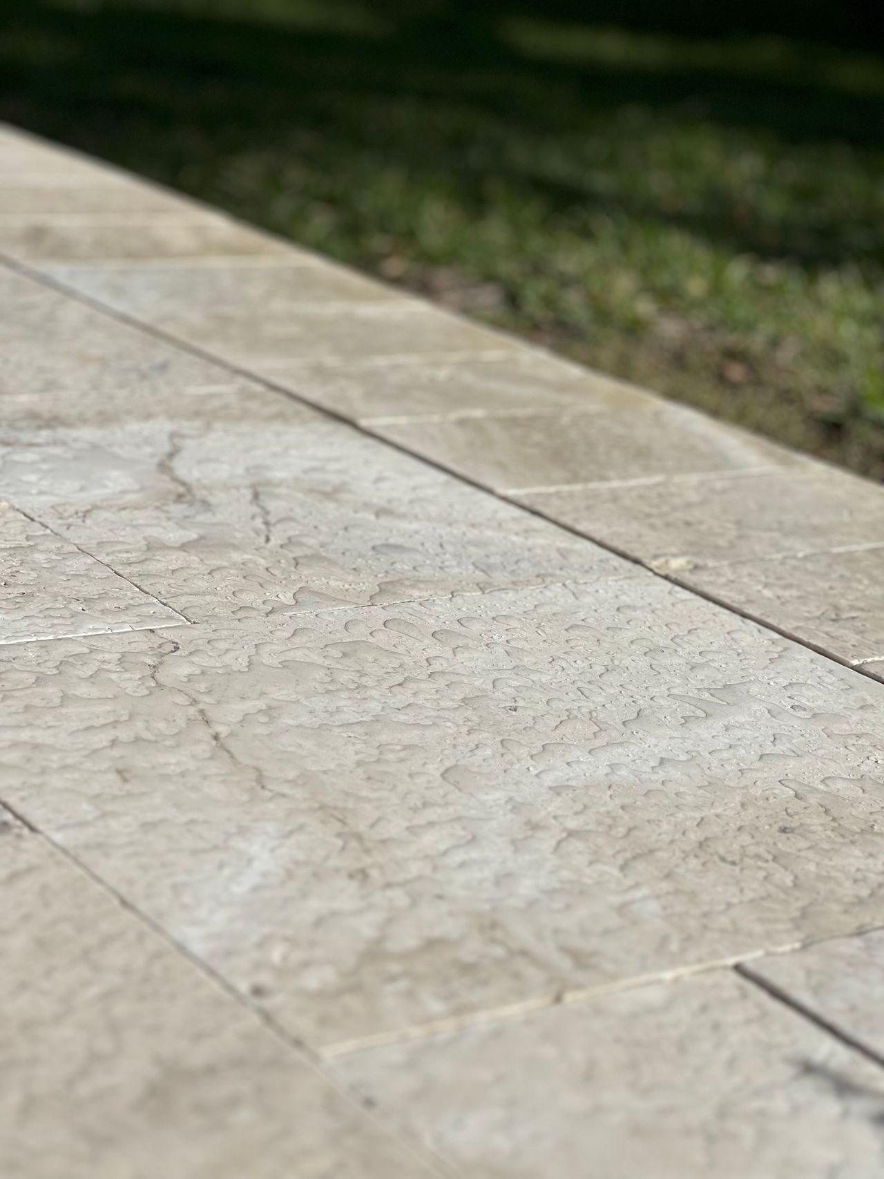 A close up of a natural stone walkway with grass in the background.