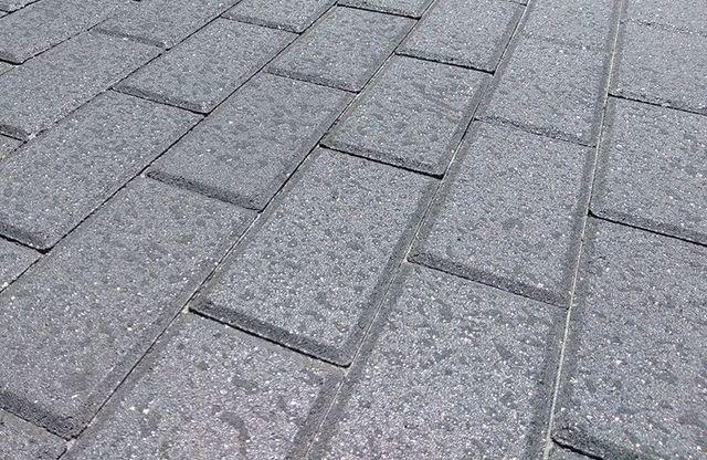 A close up of a sealed brick paver deck repelling water.