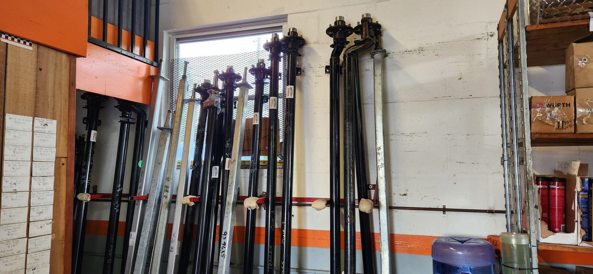 Racks of skis and poles stored in a warehouse or garage against a white wall
